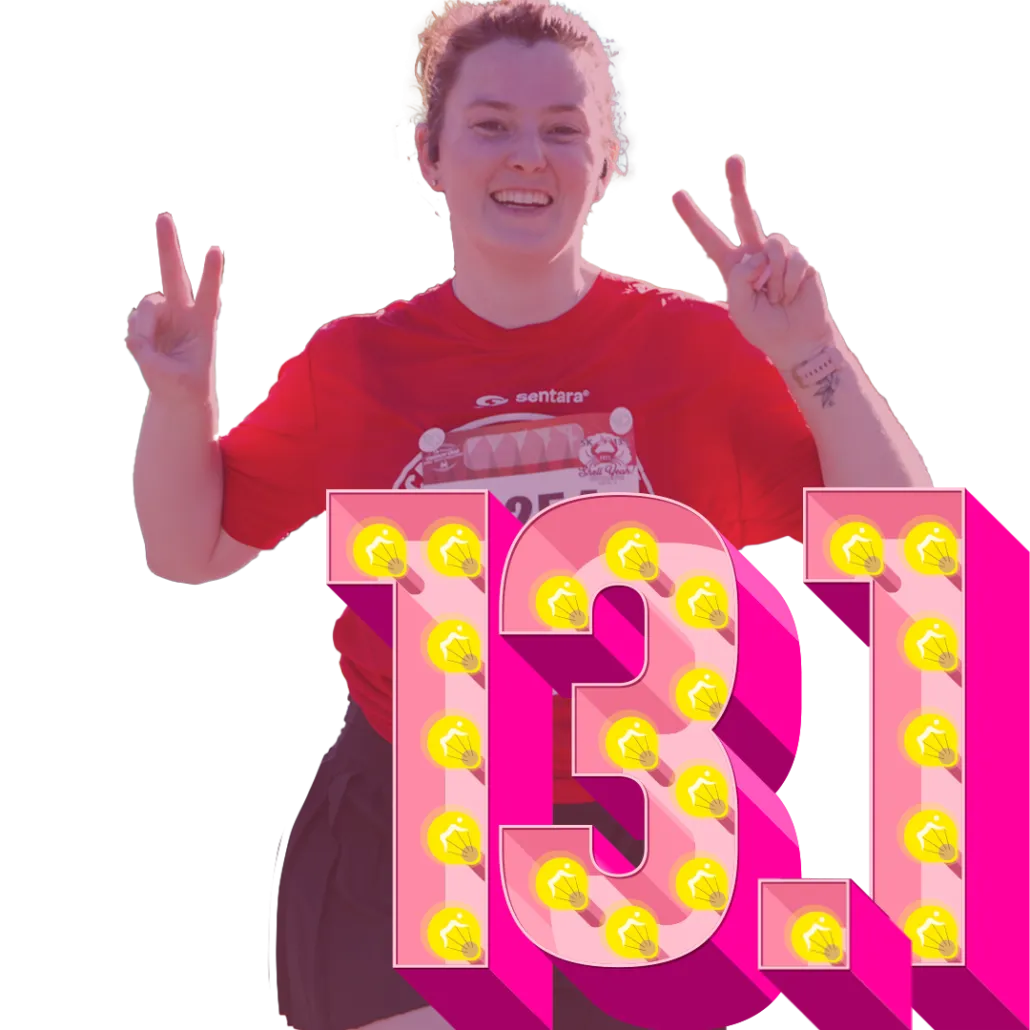 A smiling runner gives a peace sign with both hands in front of a large pink '13.1' graphic decorated with light bulbs.