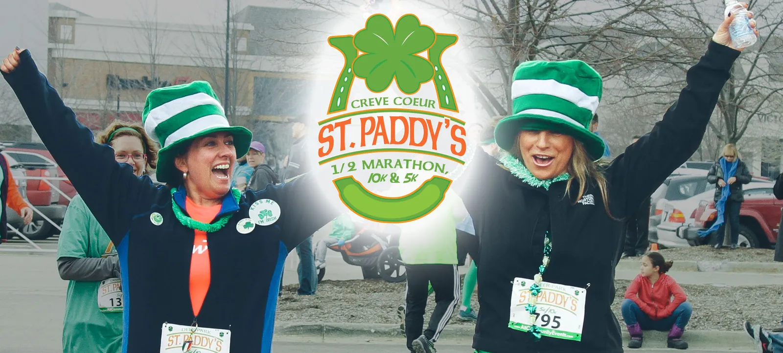Two women in green and white striped hats cheer with their arms raised at the St. Paddy's Day 1/2 Marathon, 10K & 5K race.