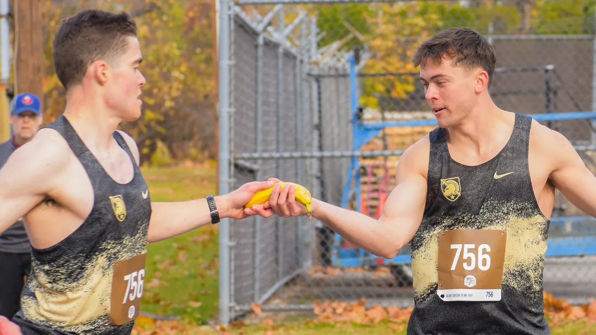 Two runners in racing singlets exchange a banana during a race.