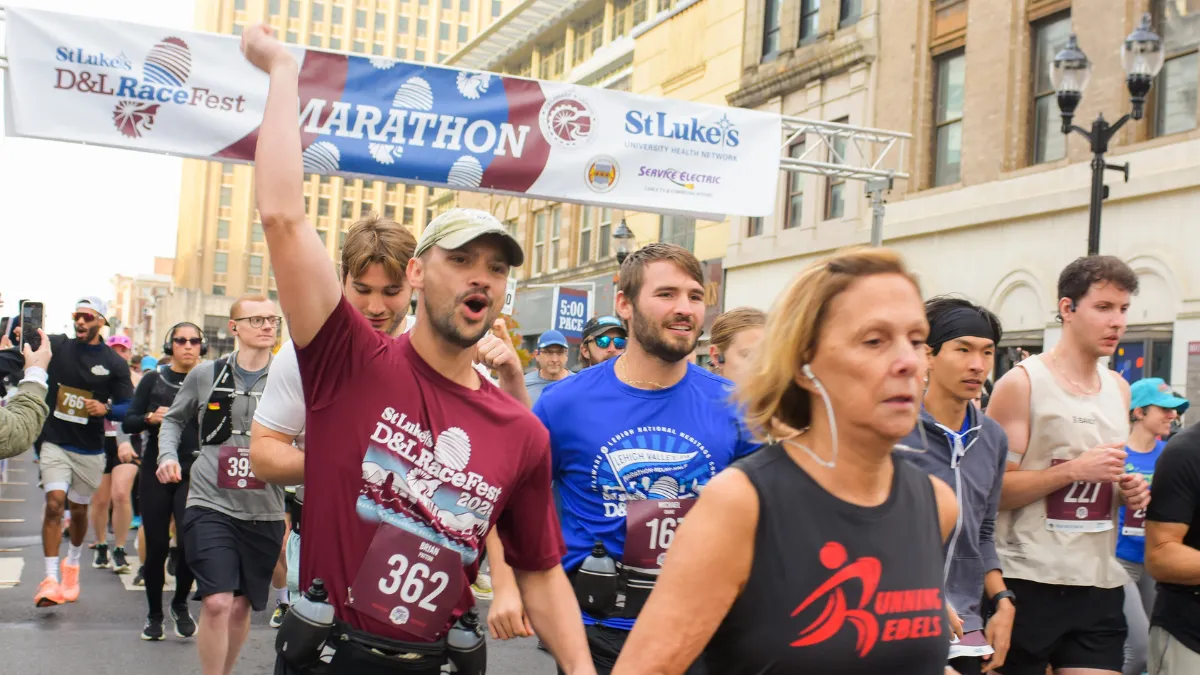 Runners at the start line of the D&L RaceFest Marathon, with one runner raising his fist in excitement.