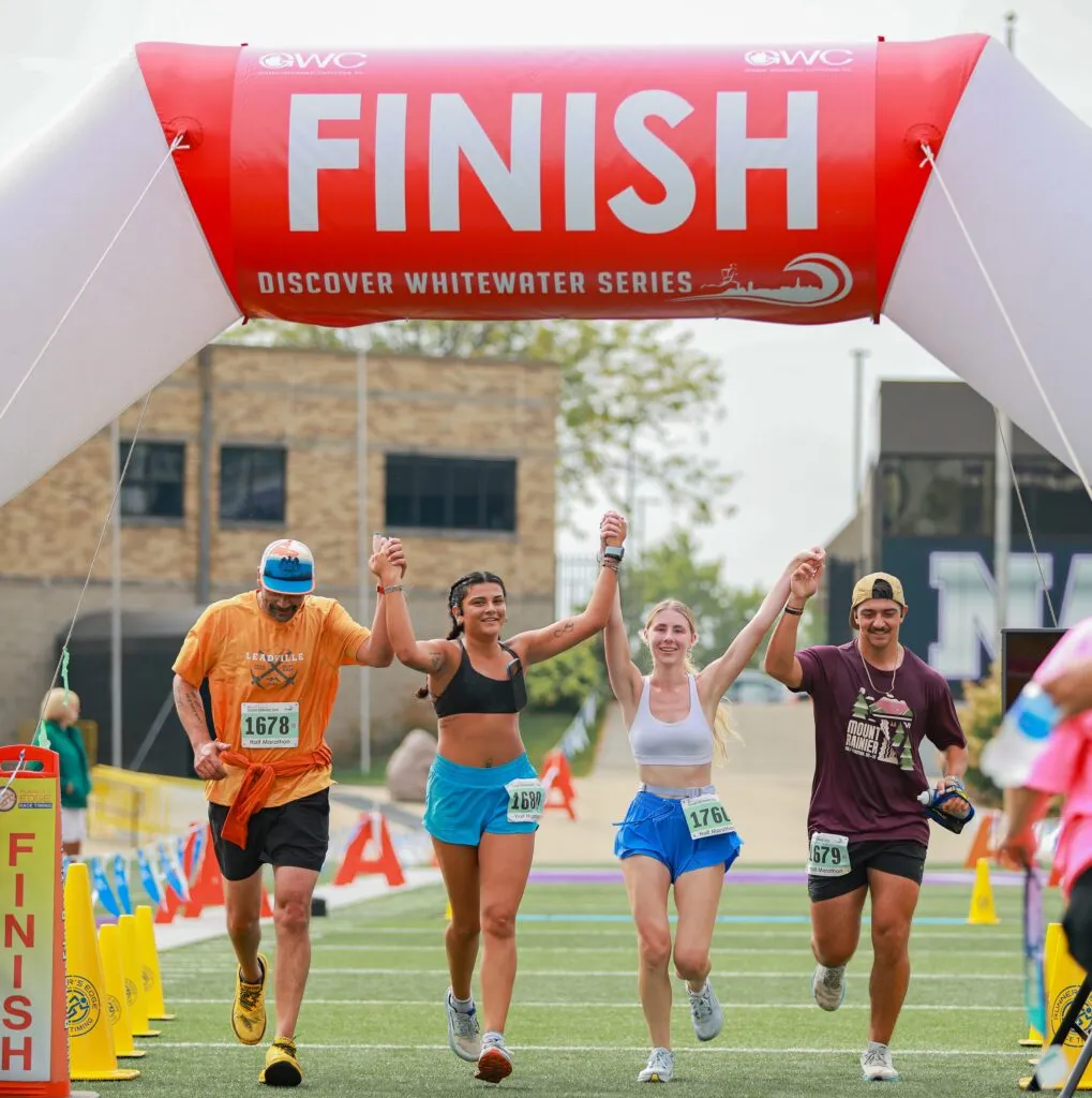 Runners crossing the finish line with their arms raised in celebration.