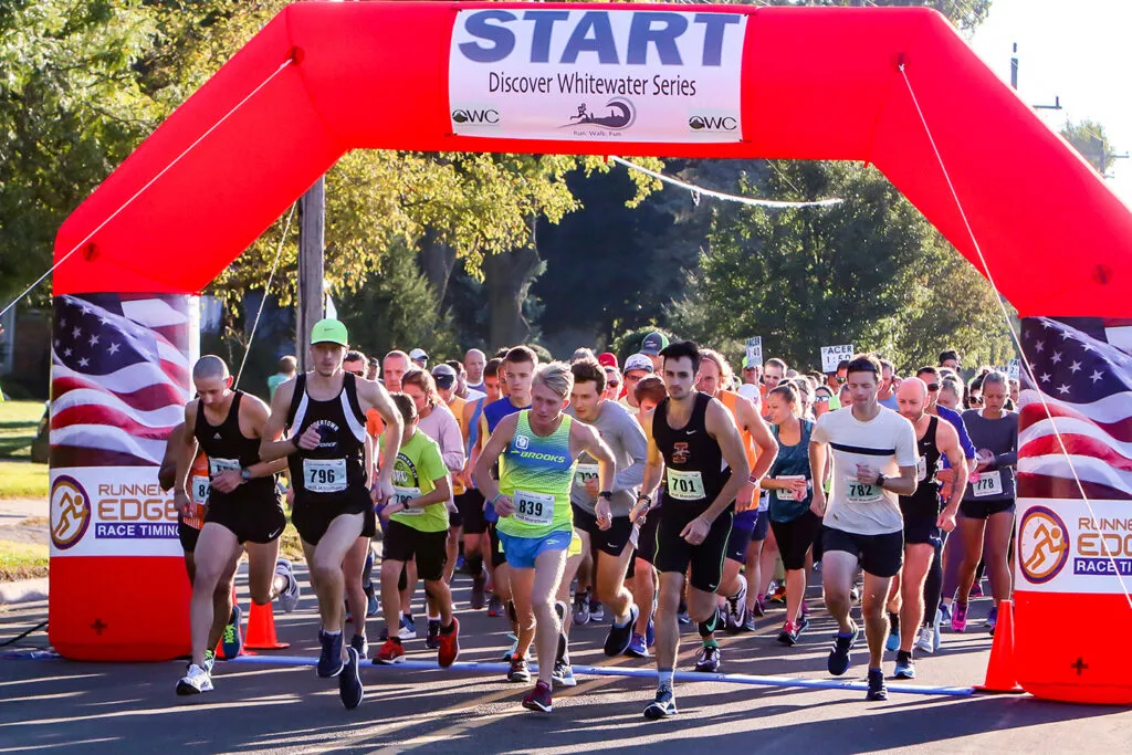 Runners starting the Discover Whitewater Series half marathon under a red inflatable arch.