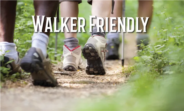 Close-up of people's feet walking on a trail with trekking poles, with the text 'WALKER FRIENDLY' overlaid.
