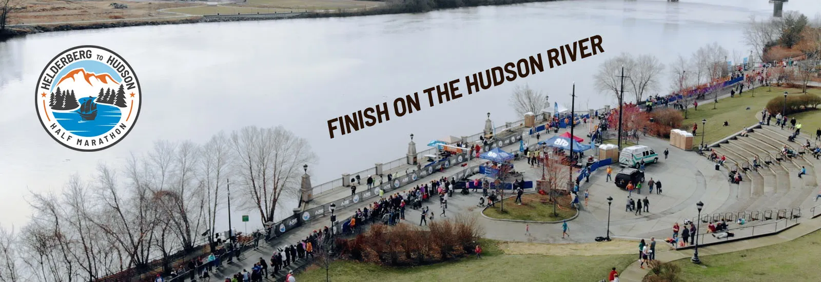 A view of the Helderberg to Hudson Half Marathon finish line on the Hudson River, with crowds of runners and spectators gathered.