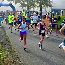 Runners starting a race, with a finish line arch in the background.