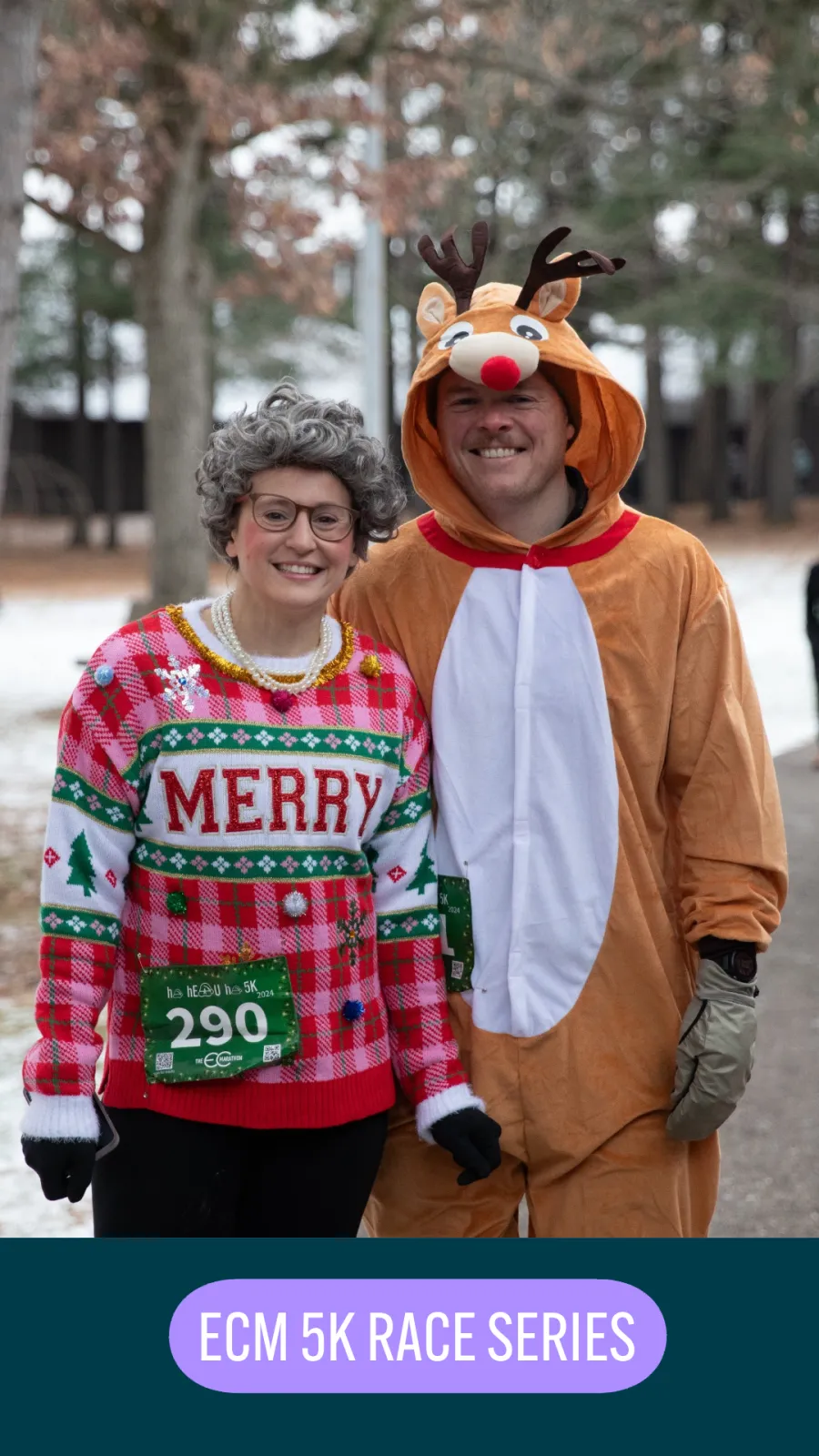 Two people in festive costumes, one dressed as a reindeer and the other in a Christmas sweater, smiling at the camera during a race.