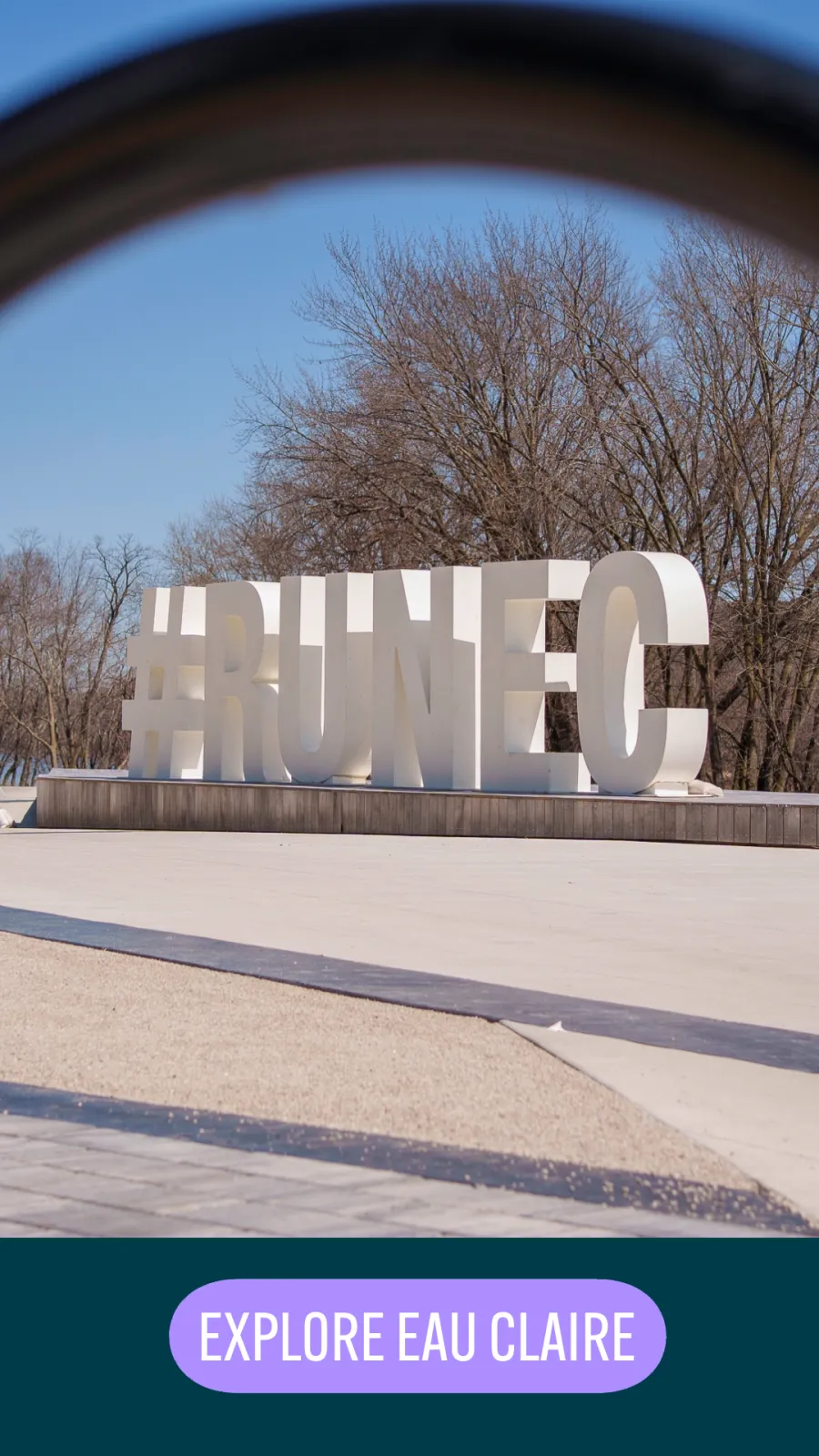Large white letters spelling out #RUNEEC in an outdoor setting with bare trees and a clear blue sky.