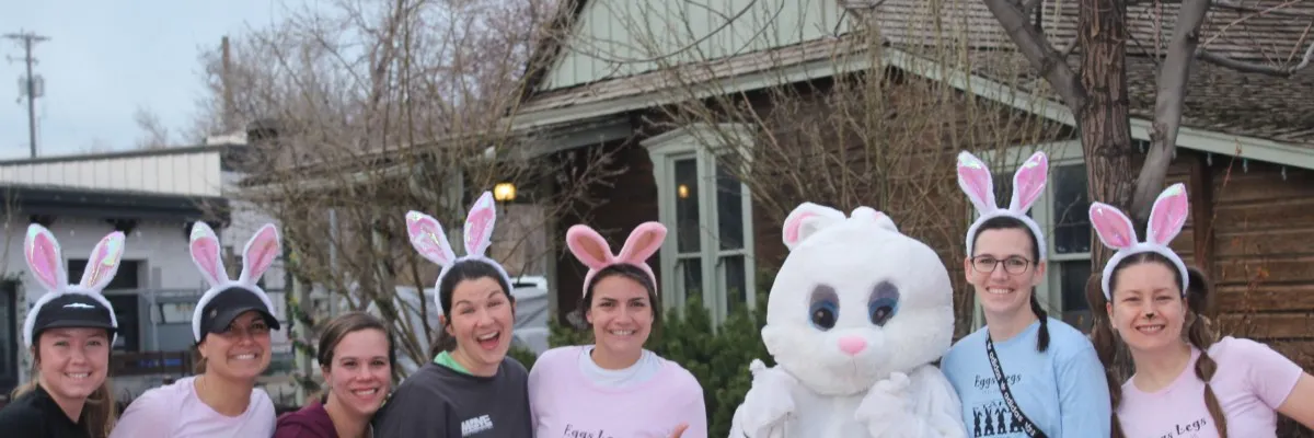 A group of people, including one in a bunny costume, wearing bunny ears and smiling.