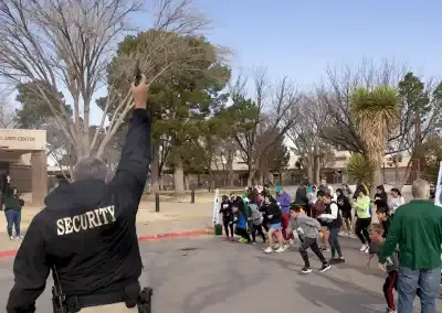 Runners lined up at the start of a race, with a security guard raising his arm to signal the start.