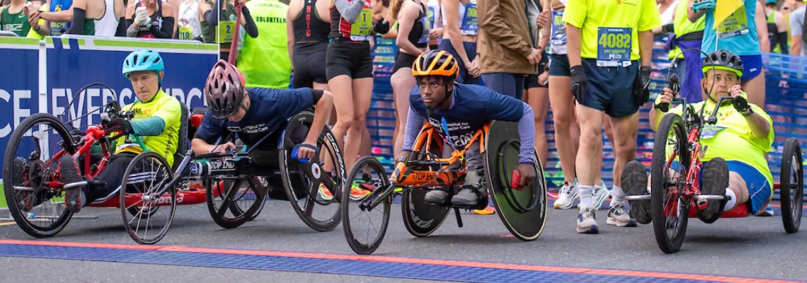 Participants in racing wheelchairs at the start line of a road race.