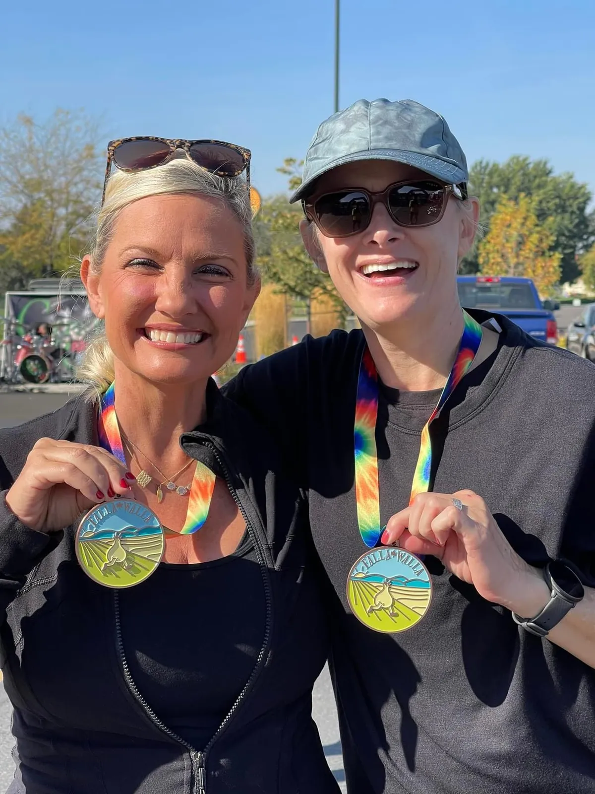 Two smiling women proudly display their race medals after completing the Falla Walla Half Marathon.