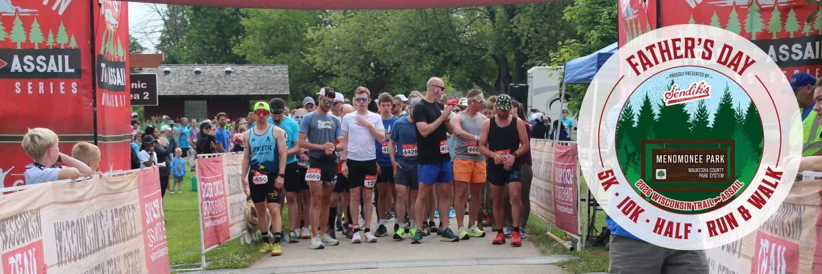 Runners lined up at the start of the Father's Day Run, with banners and a crowd visible.