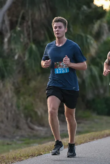 A male runner with bib number 4751 runs on a paved path with trees in the background.