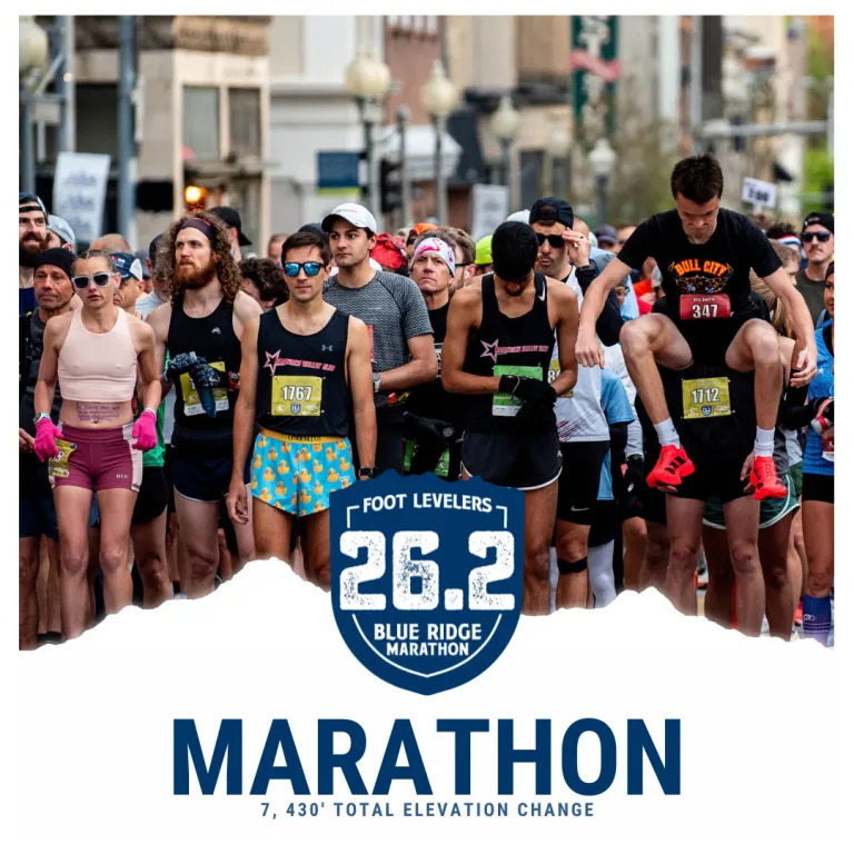 A crowd of runners at the start line of the Blue Ridge Marathon, with one runner giving another a piggyback ride.