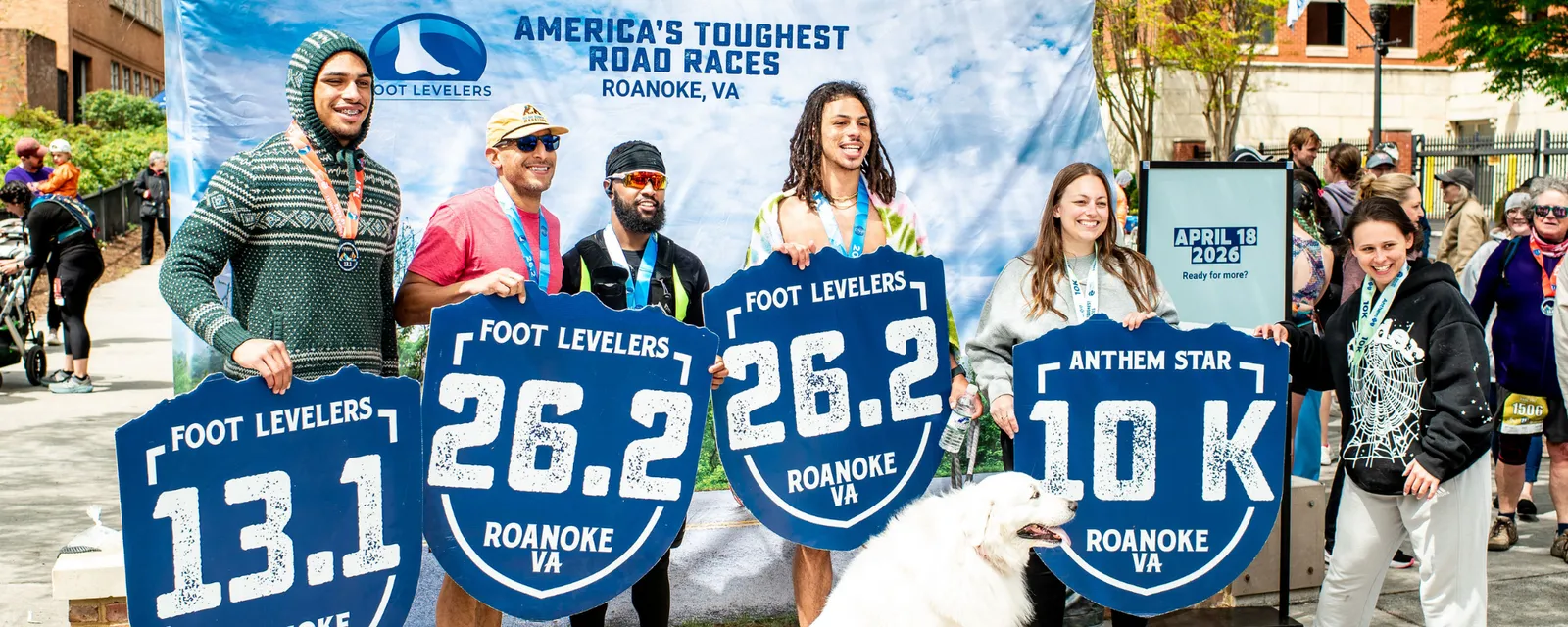 Runners holding large blue signs indicating race distances (13.1, 26.2, 10K) at the Blue Ridge Marathon in Roanoke, VA.
