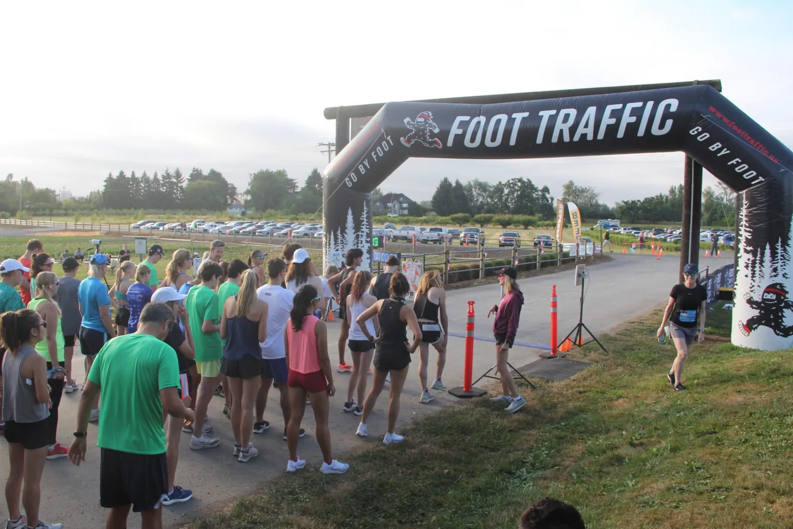 A crowd of runners gathered at the start line of a race, under an inflatable archway with 'FOOT TRAFFIC' branding.