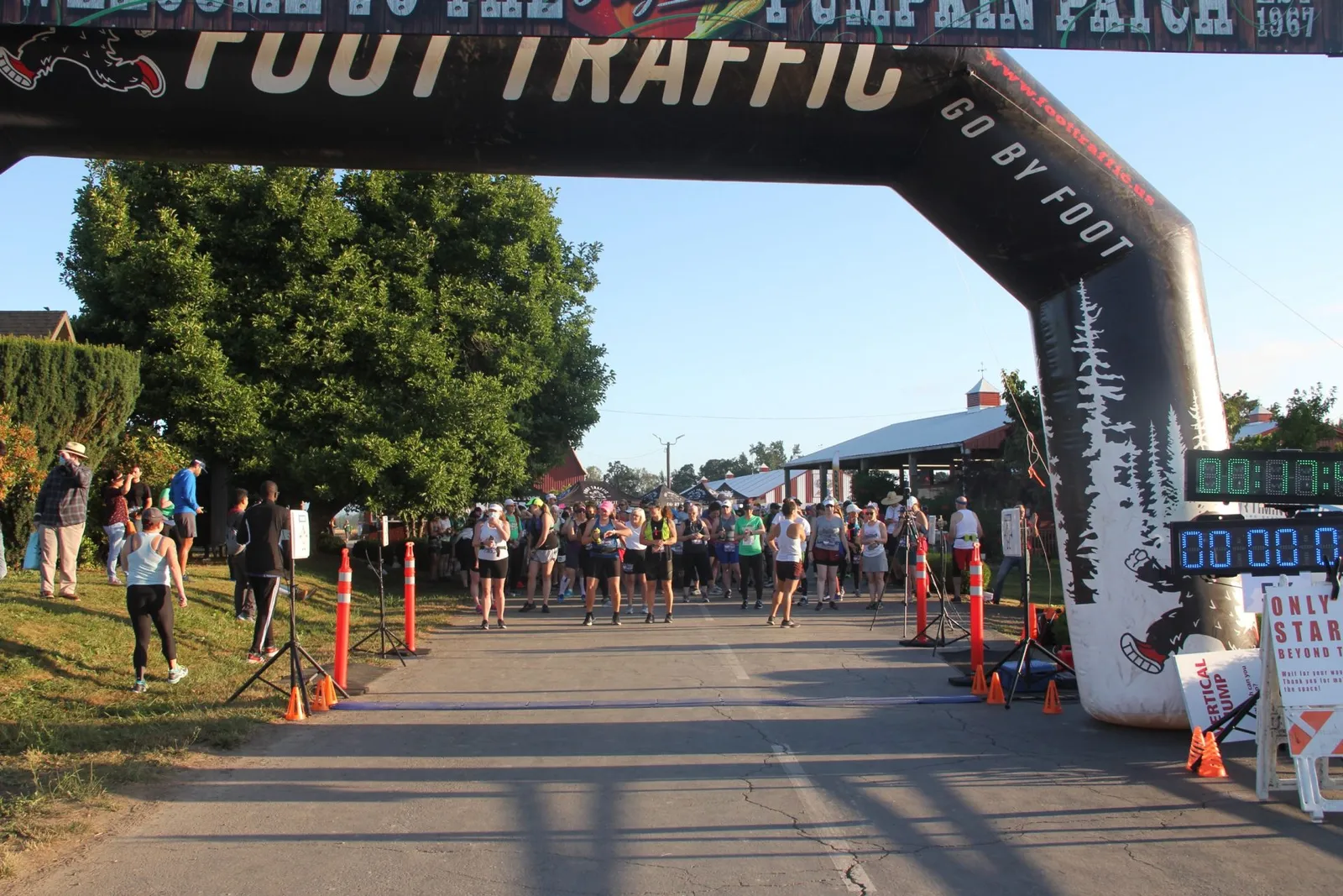 Runners gathered at the start line under an inflatable archway, with trees and buildings in the background.