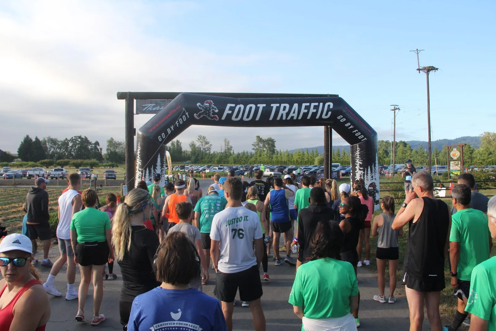 A crowd of runners gathers at the start line under a large inflatable archway that says "FOOT TRAFFIC".