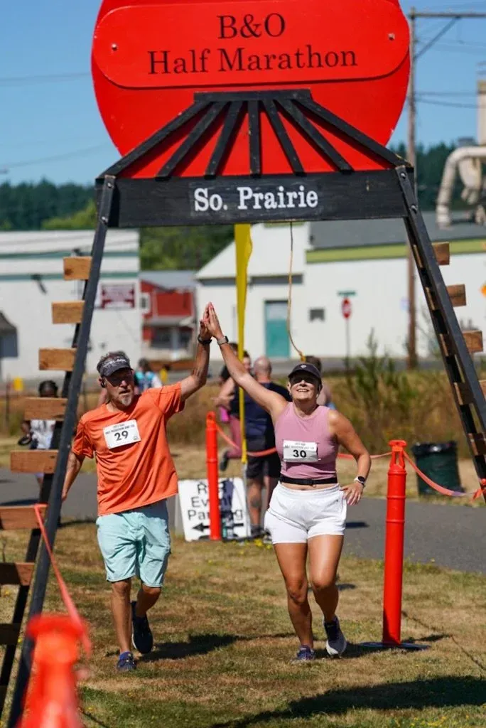 Two runners high-fiving at the finish line of the B&O Half Marathon.