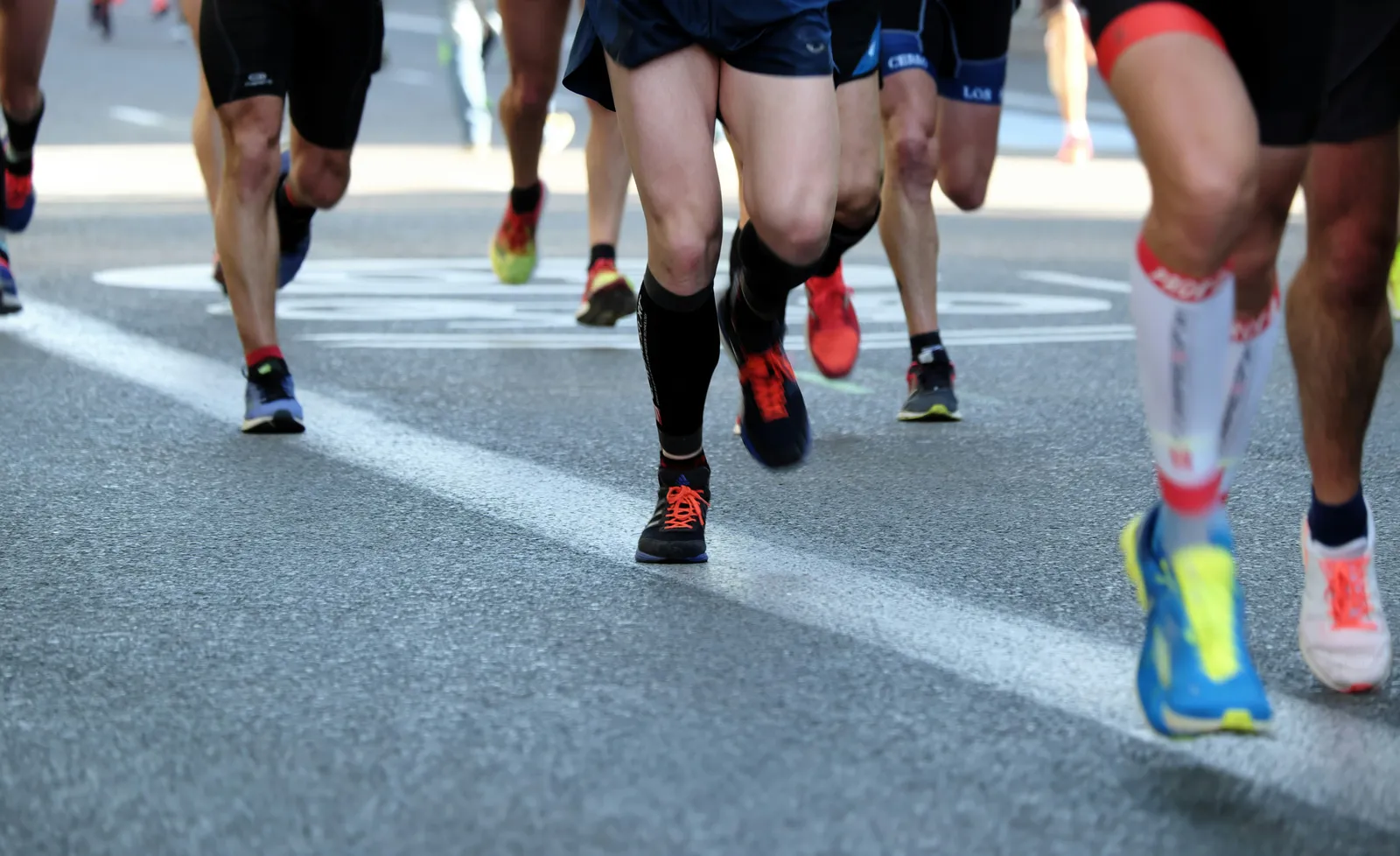 Close-up of runners' legs and feet as they race on a road course.