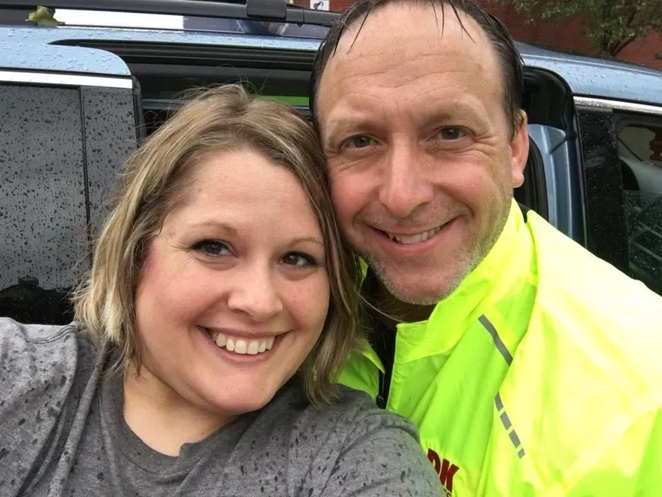 A smiling woman and a smiling man pose for a selfie, likely before or after a race.