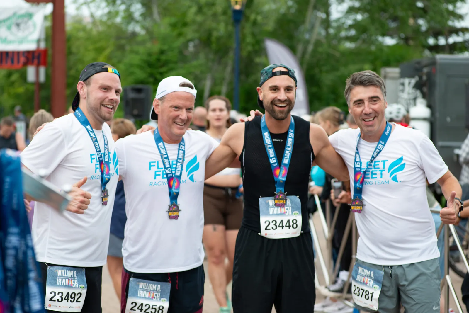Four smiling runners, wearing medals and race bibs, pose together after completing a half marathon.