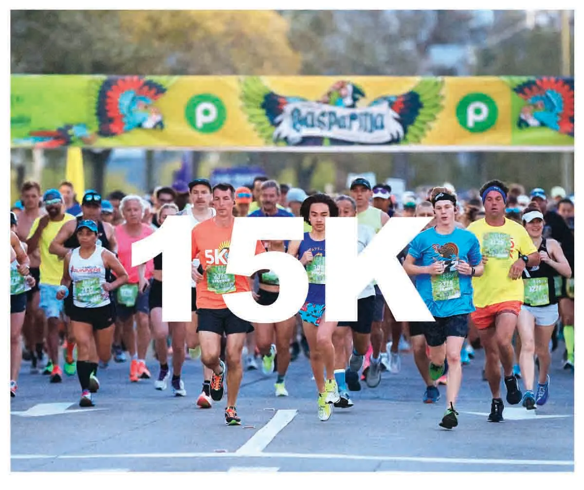 A large group of runners are starting a 15K race, with a banner overhead that says 'Gasparilla'.