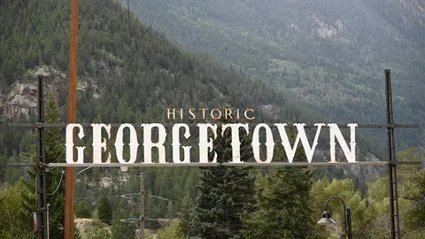 Historic Georgetown sign with mountains and forest in the background.
