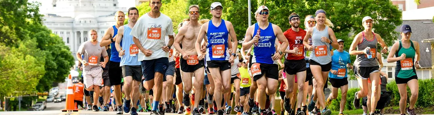 A group of runners participating in a race, with a large building in the background.