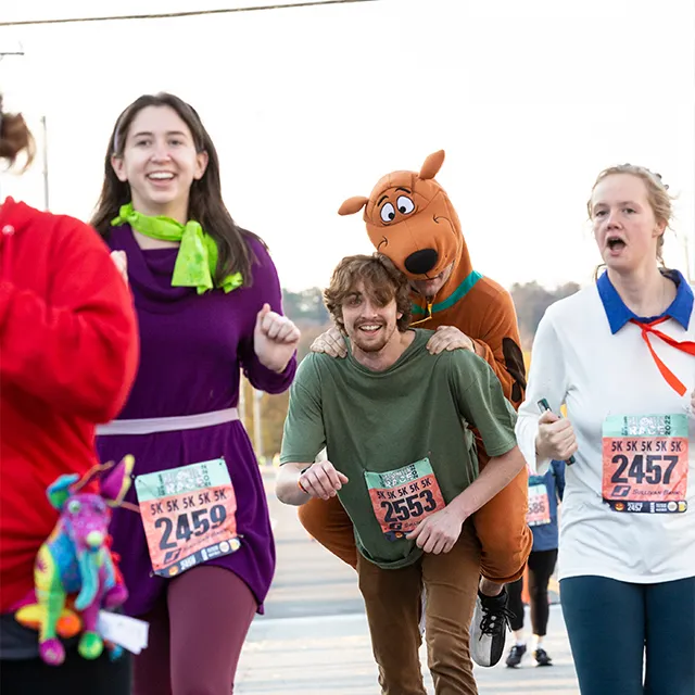 Runners in Halloween costumes, including Scooby-Doo, participating in a race.