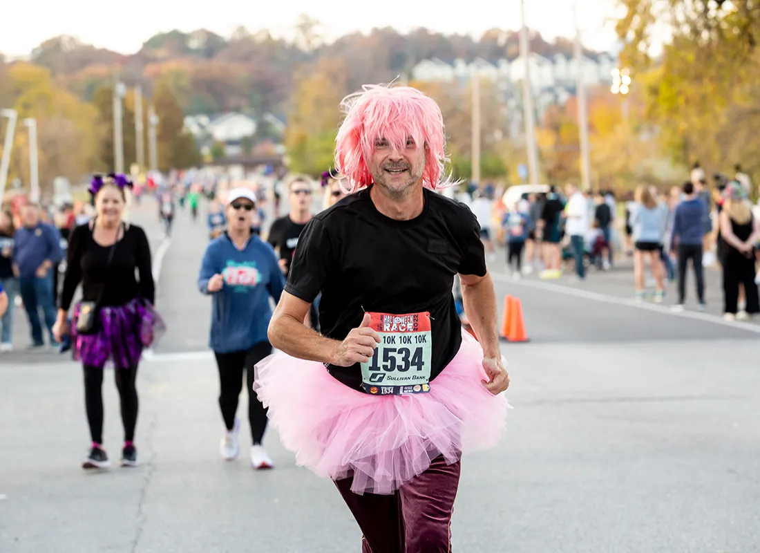 A runner wearing a pink wig and tutu gives a thumbs-up while participating in the Go St. Louis Halloween 10K/5K Fun Run.