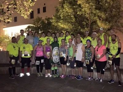 A group of runners posing for a photo at night, many wearing bright yellow shirts.