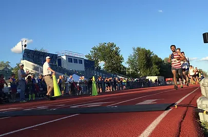 Runners starting a race on a track, with spectators watching from the sidelines.
