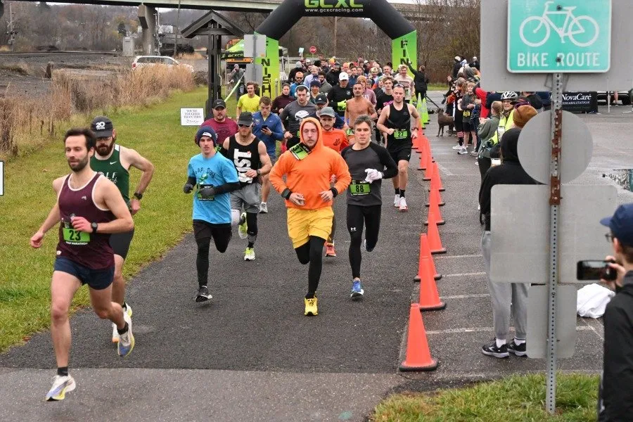 Runners starting a race, with an inflatable archway in the background and orange cones lining the course.