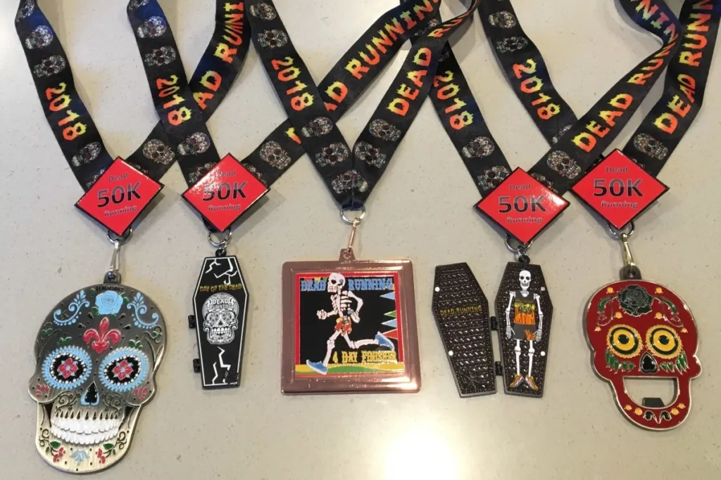 A collection of unique race medals, including skull-shaped and coffin-shaped designs, with ribbons displaying 'Dead Running 2018'.
