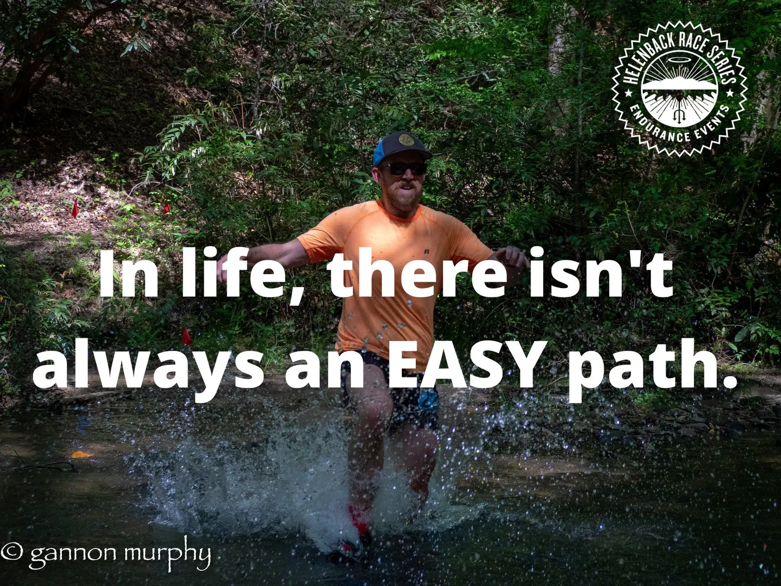 A runner in an orange shirt splashes through a shallow stream on a wooded trail, with the text "In life, there isn't always an EASY path." overlaid.