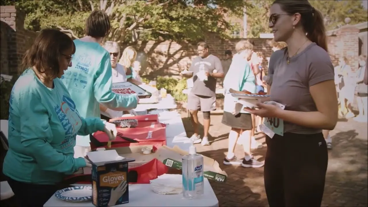 People gathered around tables with food and drinks after a race, with some wearing race bibs.