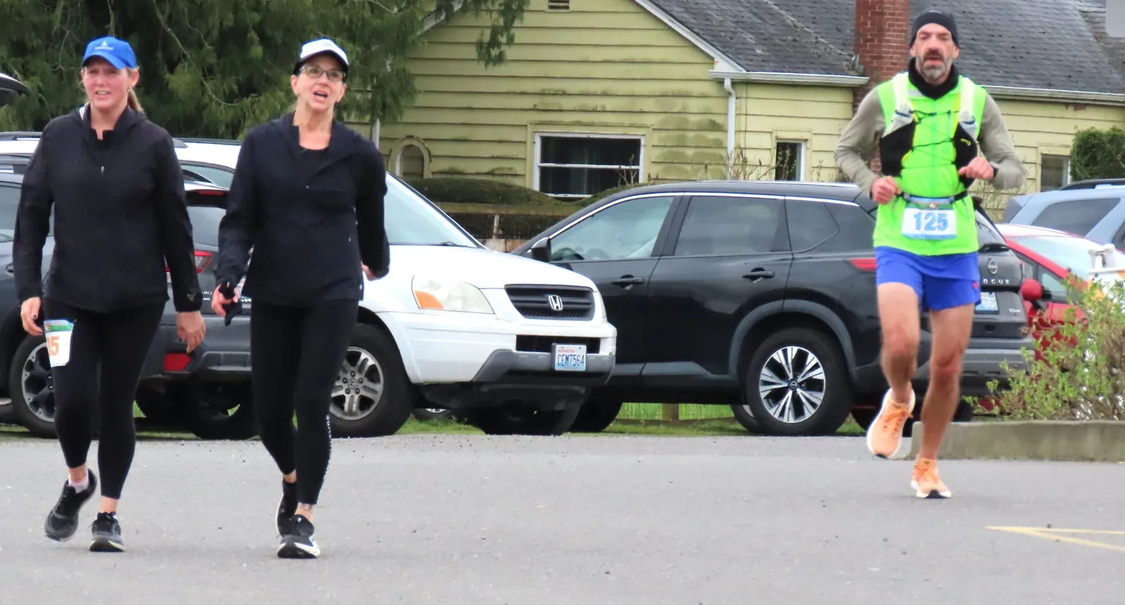 Three runners on a road, one in the foreground with a bib number 125.