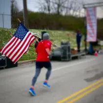 Runner carrying an American flag during a race.