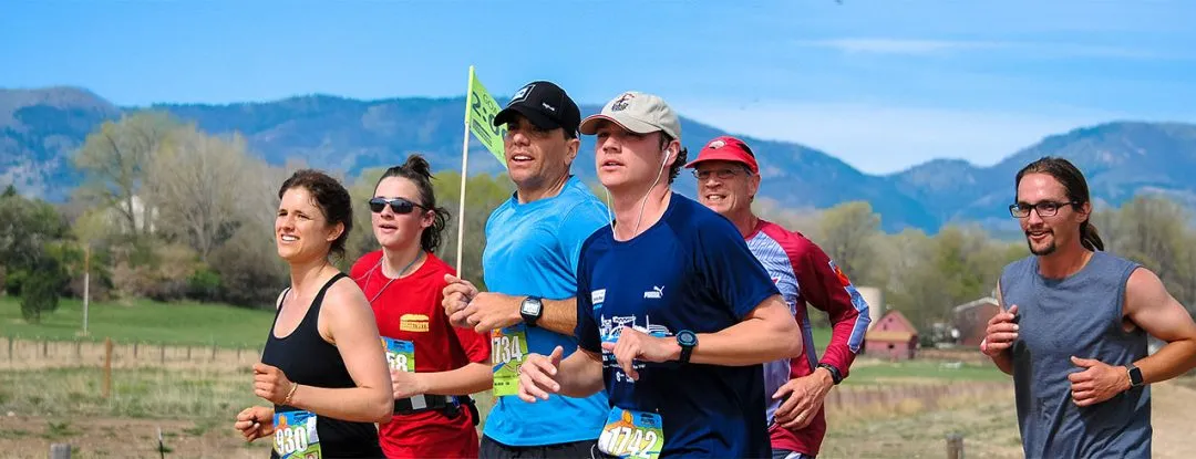 A group of runners on a scenic course, with mountains in the background.