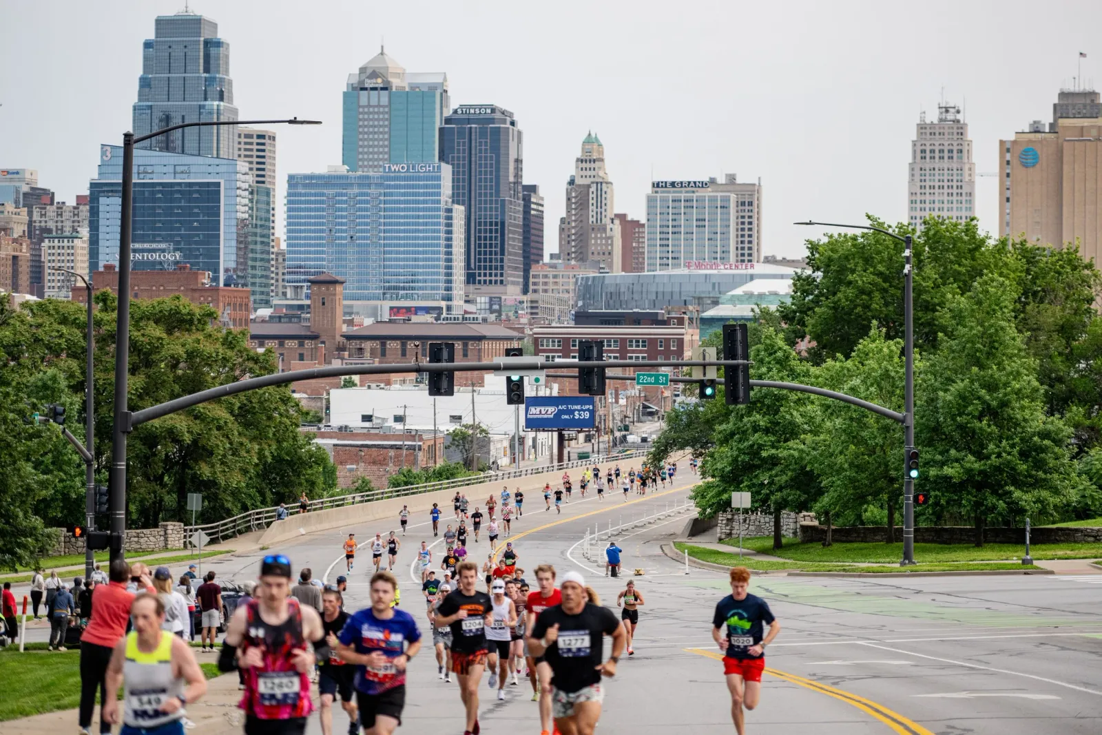 Runners on a city street with skyscrapers in the background during the Hospital Hill Run.