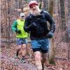 Two runners on a wooded trail in the fall.