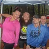 Four runners smiling and posing for a photo under a tent at a race event.