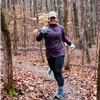 A woman runs on a wooded trail in the fall.