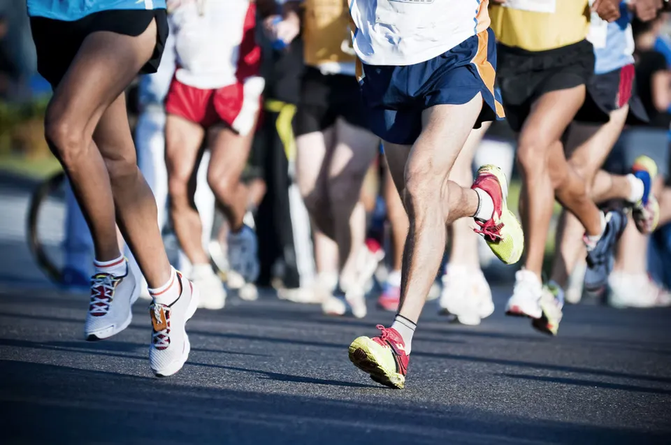 Close-up of runners' legs and feet as they race on a road.