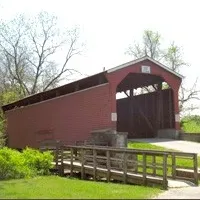 A red covered bridge with a wooden walkway leading up to it.