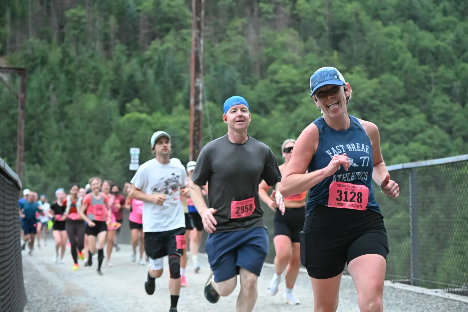 A group of runners on a road, with the lead runner smiling and sticking her tongue out.