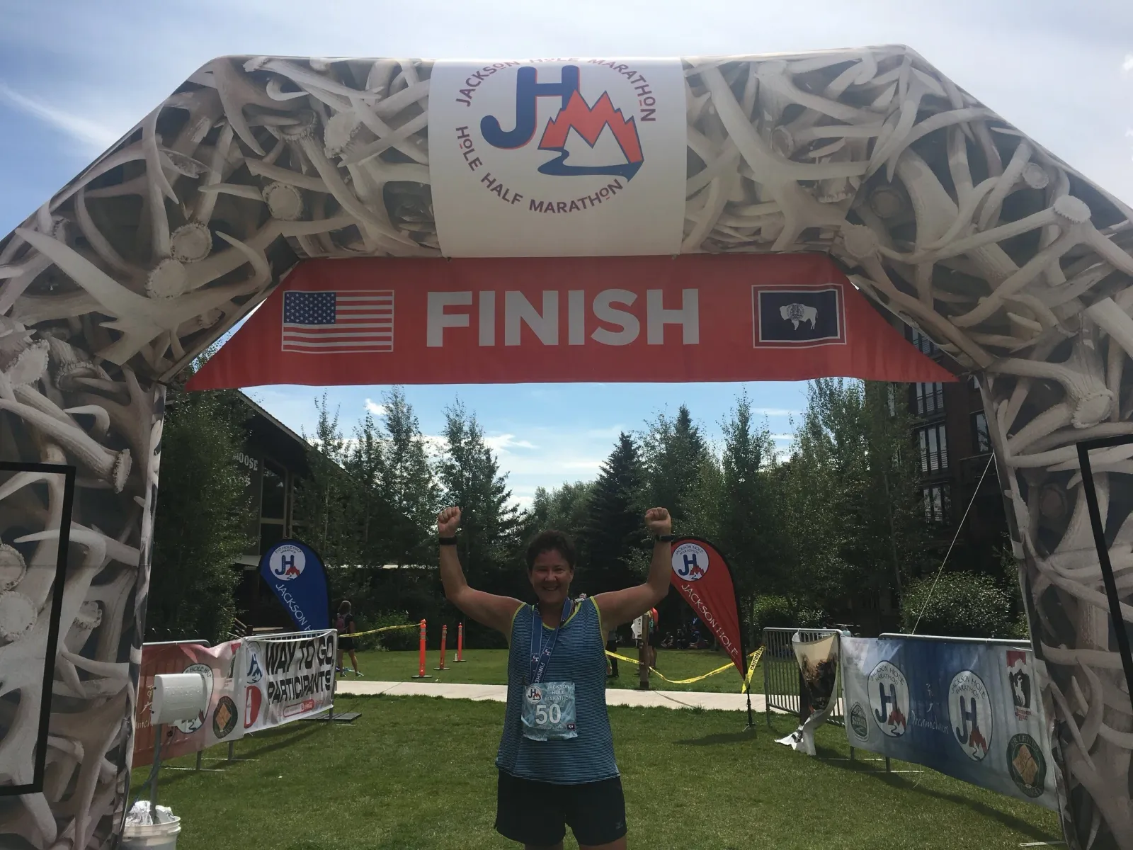 A runner with arms raised in celebration crosses the finish line at the Jackson Hole Half Marathon.
