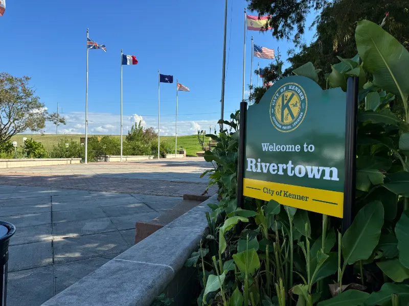 Welcome to Rivertown sign with flags in the background.