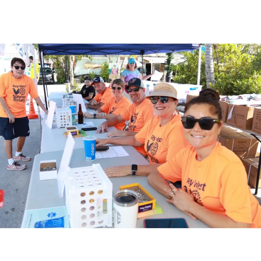 Volunteers in orange shirts smile at a registration table for the Key West race.